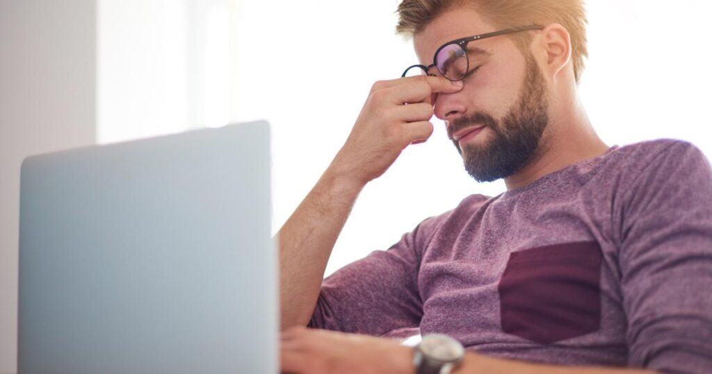 Frustrated person holding their head at a laptop because they forgot password again.