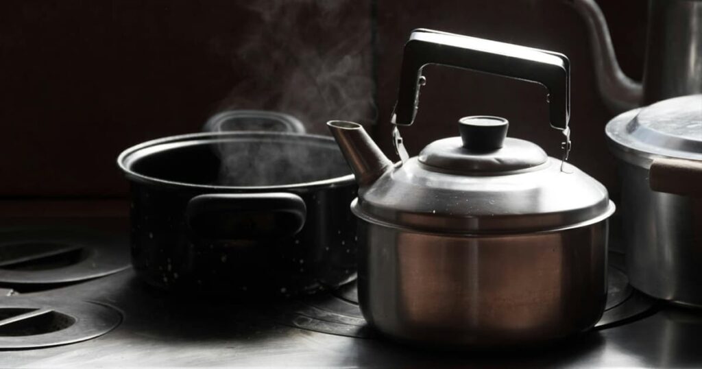 A boiling electric kettle in a kitchen, representing heating water manually.