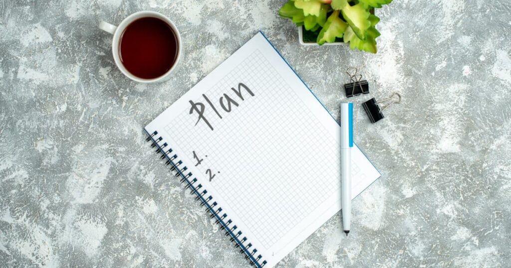 A hand writing a to-do list in a notebook to clear the mind of worries.