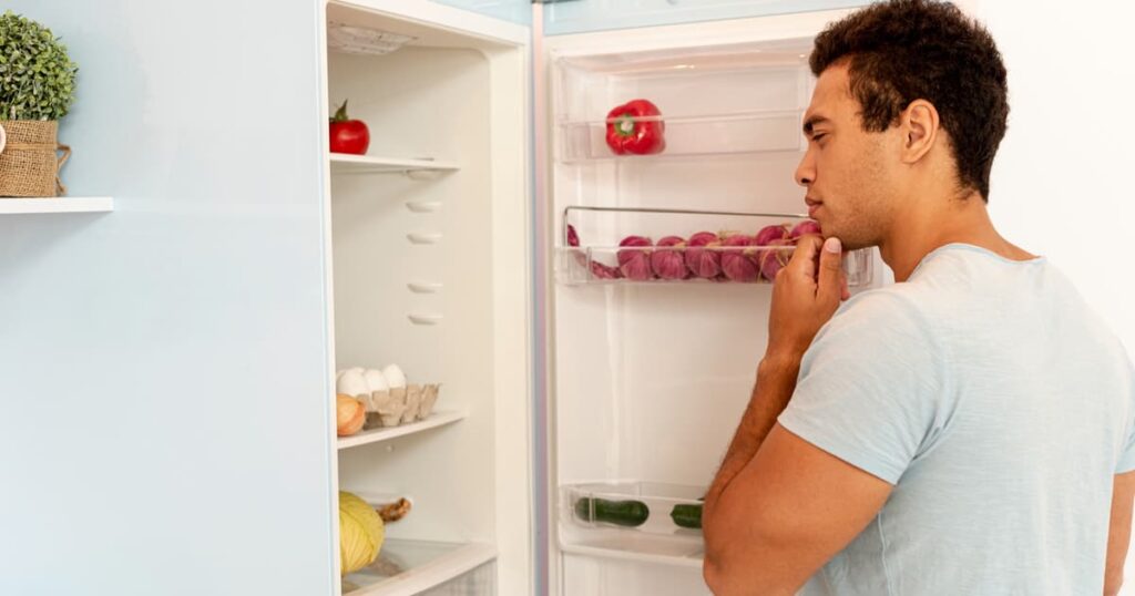 A person looking at a sticky note or open fridge with a confused expression, forgetting what they needed.