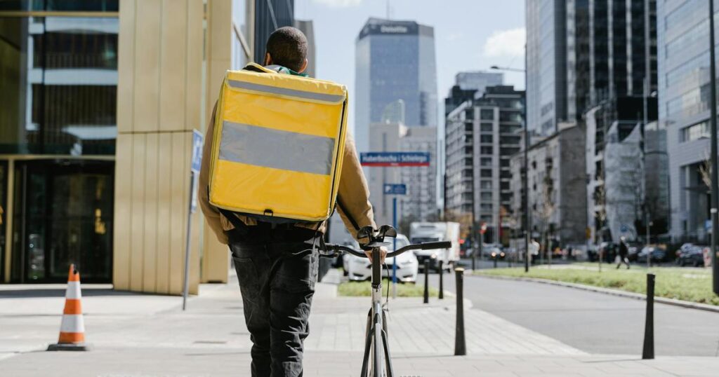 A person struggling to carry a giant, heavy backpack labeled Stuff representing the burden of possessions.