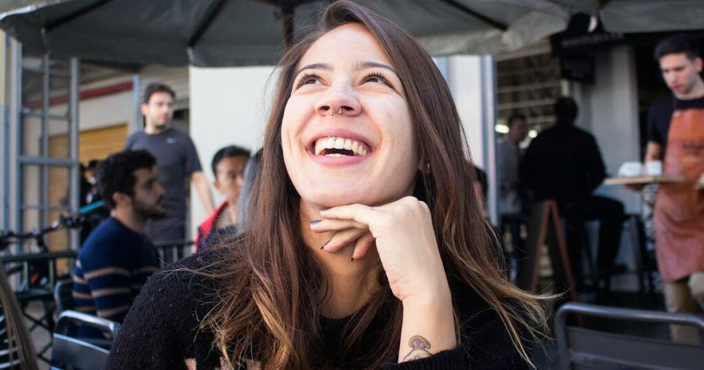 A person laughing and moving naturally while having their photo taken, looking relaxed.