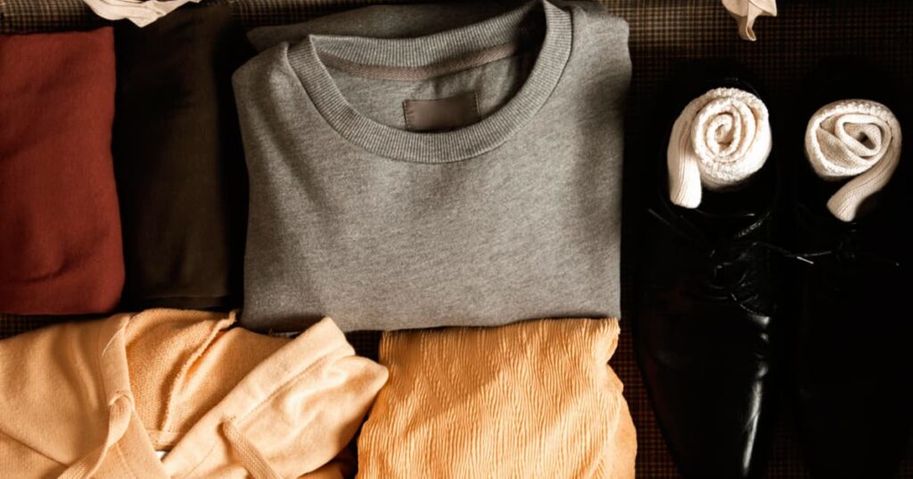 A neat grid of clothing items laid out on a bed following the 5-4-3-2-1 packing rule.