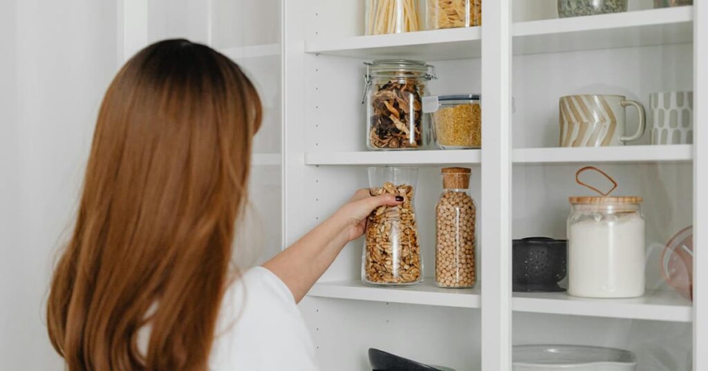 Clear plastic storage bins on a shelf filled with items, showing how to organize without hiding things.