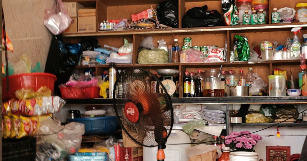 A cluttered pantry overflowing with food boxes and cans, looking messy and overwhelming.