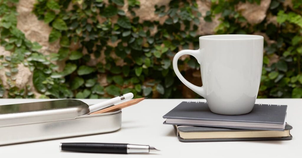 A messy coffee table with books, mugs, and a remote, looking lived-in but not dirty.