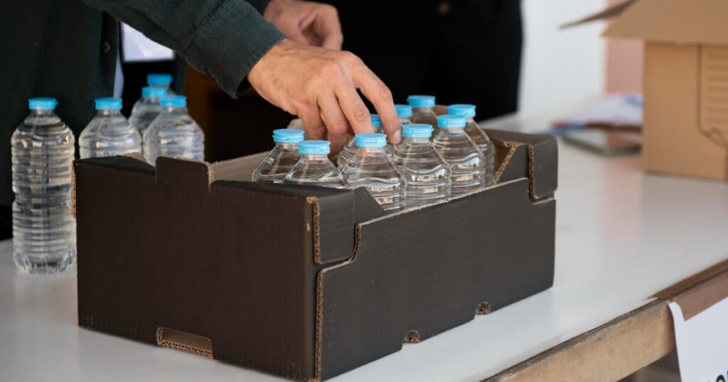 A stash of granola bars and bottled water being packed into a bag.