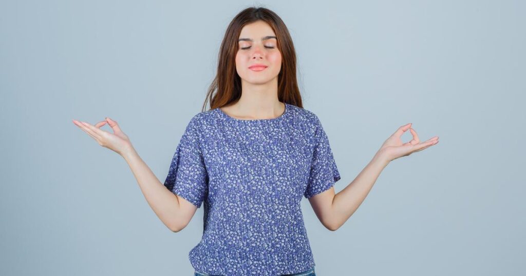 A person looking calm and peaceful while holding up a hand to stop negative energy or noise.