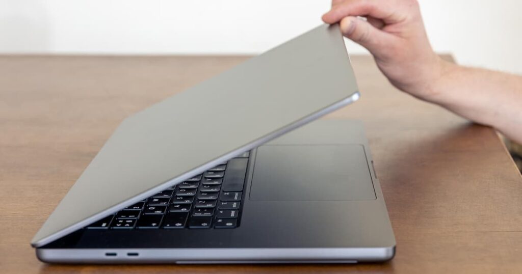 A person closing their laptop with a satisfied smile, having finished work early by single-tasking.