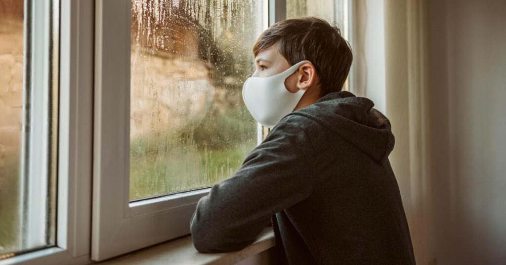 An artistic image of a person standing behind a glass wall, protected from a storm outside.