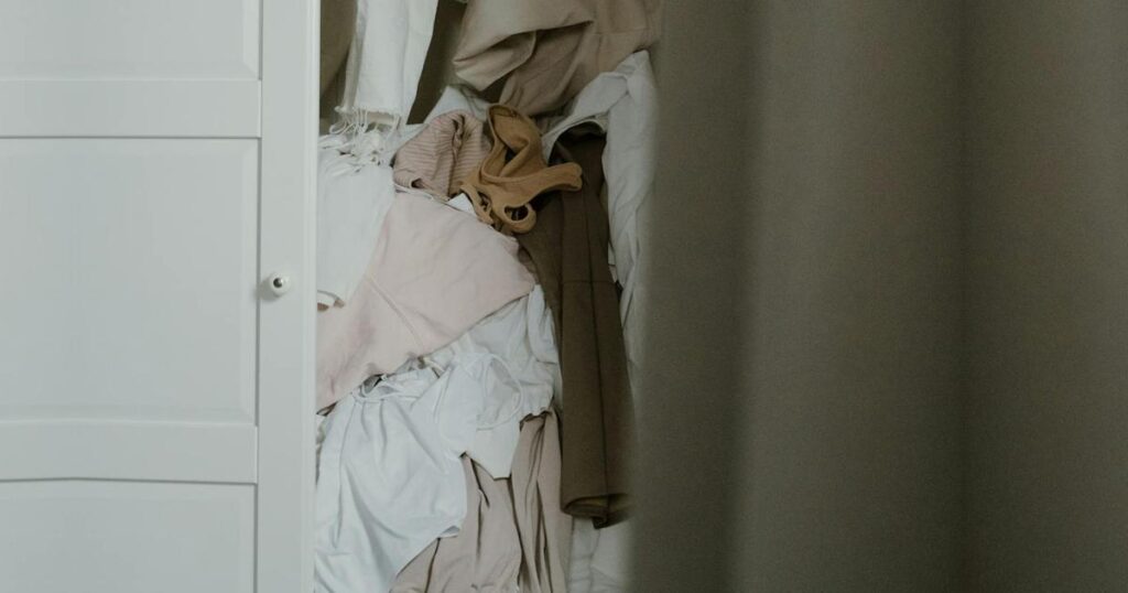 A close up of a messy closet rack with clothes jammed together tightly.
