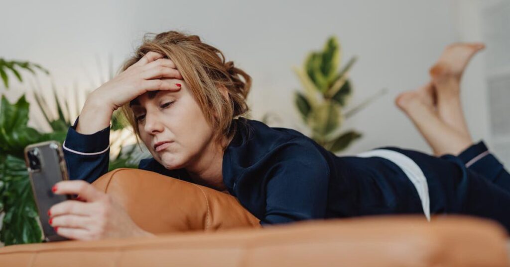 A person looking at a bank statement on their phone with a worried expression about monthly fees.