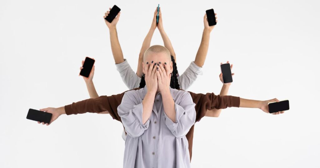 Illustration of a stressed person trying to juggle phones, laptops, and coffee, representing the failure of multitasking.