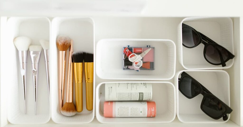 A drawer organized with small plastic bins separating pens, batteries, and miscellaneous items.