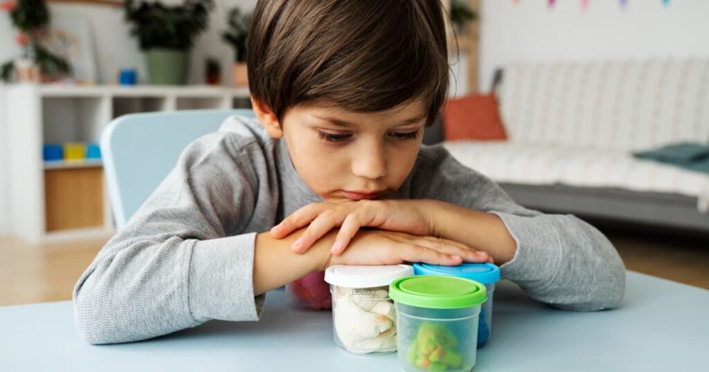 An illustration of a child looking stressed and overwhelmed by a mountain of colorful toys.