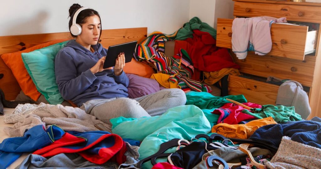 A bed covered in piles of clothes and toiletries before being packed.