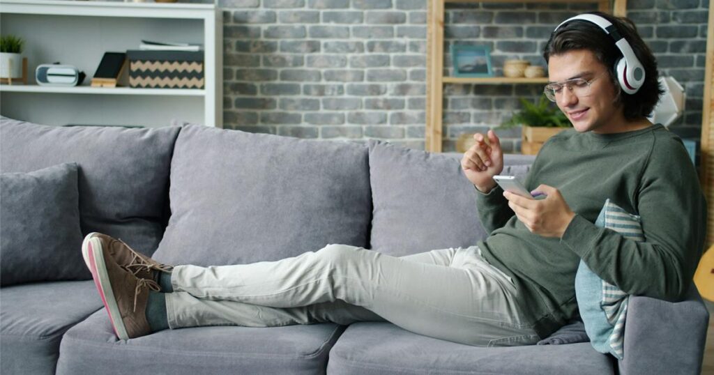 A person sitting comfortably on a sofa replying to messages during their designated time.