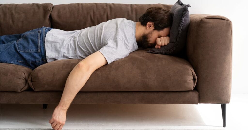 A person lying upside down on a couch looking incredibly bored and restless.