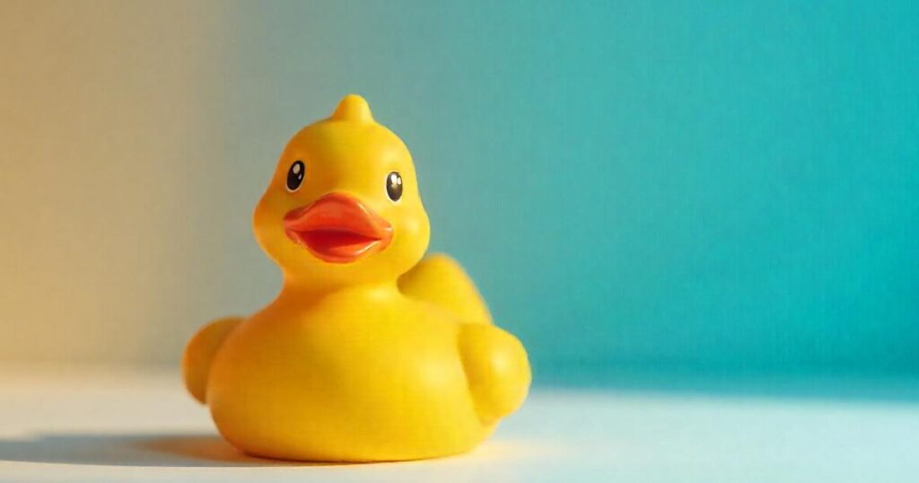 A yellow rubber duck sitting on a computer desk next to a keyboard, representing the debugging method.