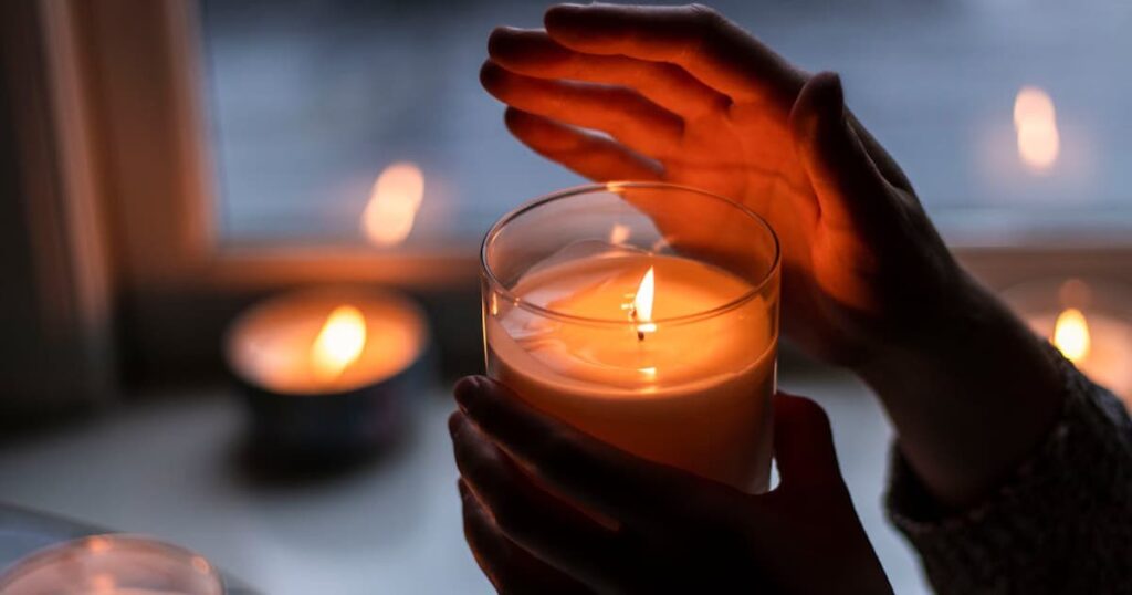 A lit scented candle and a cozy blanket, representing changing the sensory environment.