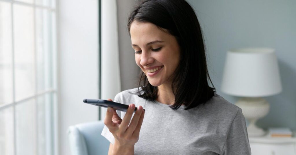 A close up of a thumb holding down the microphone button to record a voice note on a phone