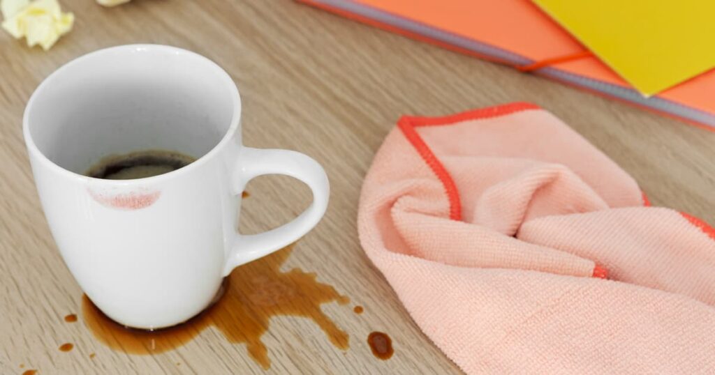 A cup of coffee spilled on a table or floor, showing clumsiness due to stress.