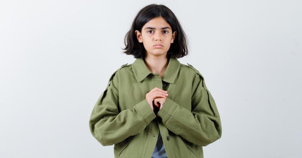 A person looking timid and apologetic, holding their hands up in a defensive gesture.