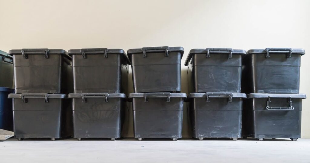 A stack of plastic storage bins sitting in a garage, representing managed clutter.