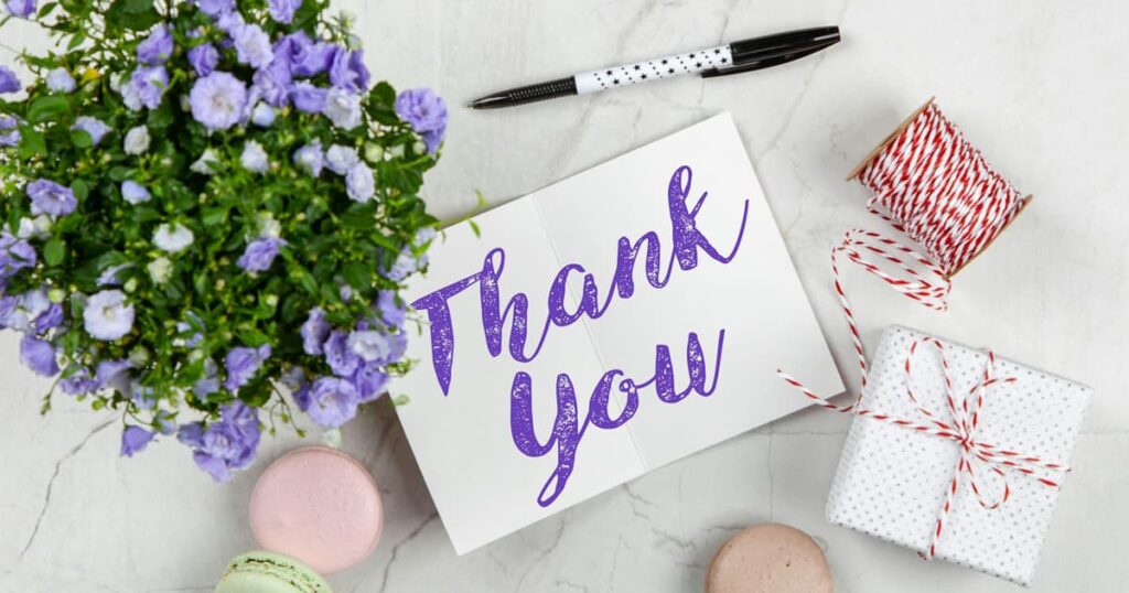 A sticky note with "Thank You > Sorry" written on it attached to a computer monitor.