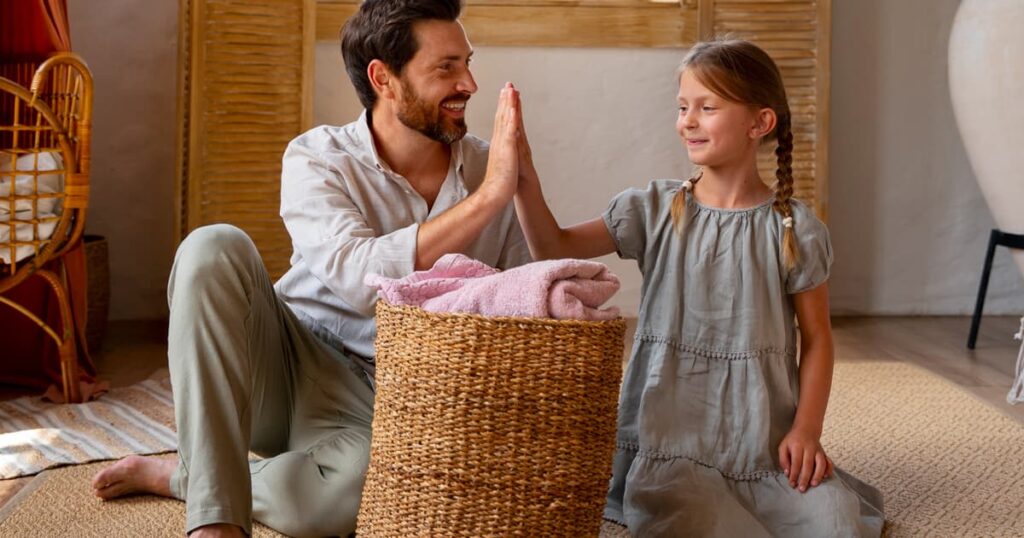 A person quickly tossing toys and clothes into a basket to tidy up before cleaners arrive.