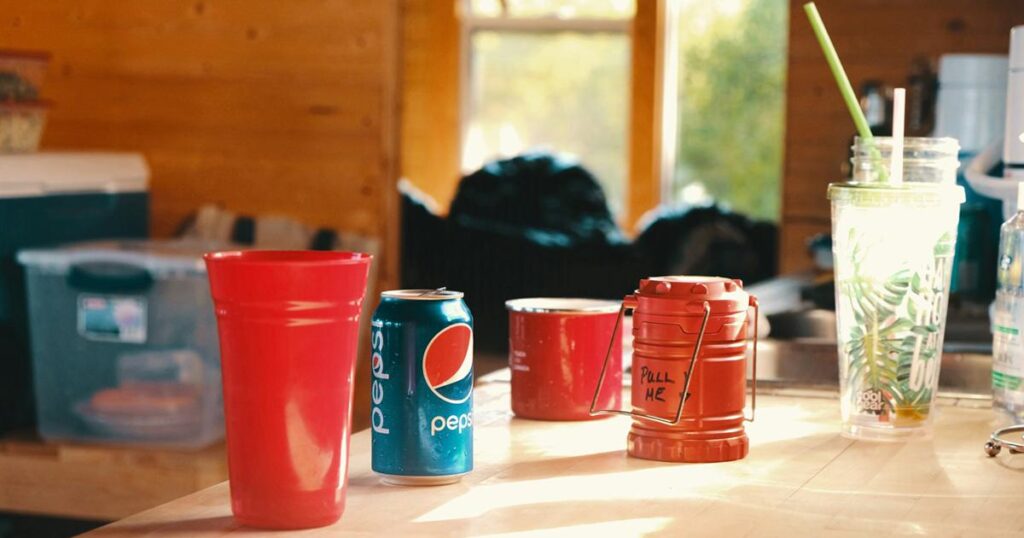 A messy desk covered in empty coffee cups and energy drink cans, showing a lack of water.