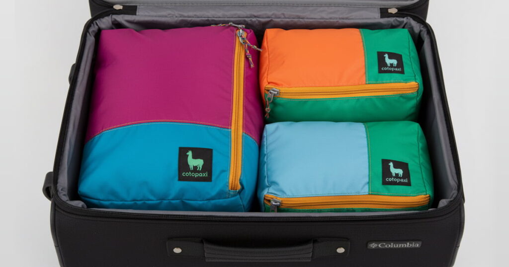 Open suitcase organized with packing cubes and travel accessories. Text overlay: 5 Ways to Pack Lighter.