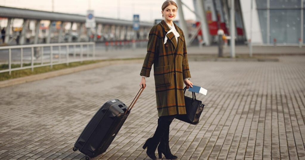 A person happily pulling a small, lightweight carry-on suitcase through an airport.