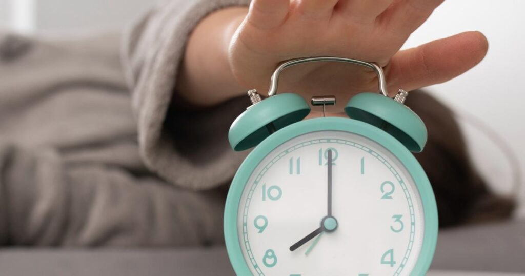 A person waking up instantly at the sound of an alarm without hitting snooze.