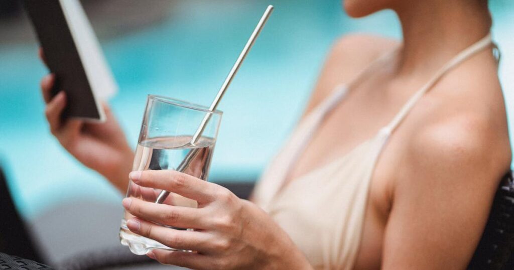 A large reusable water bottle with a straw sitting on a work desk.