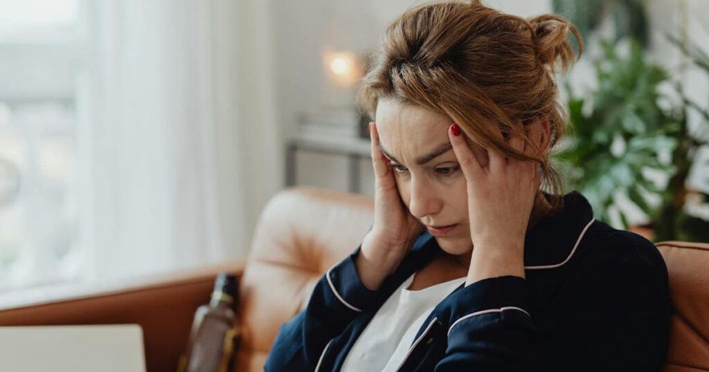 A person looking confused and touching their temple, experiencing a headache or brain fog.